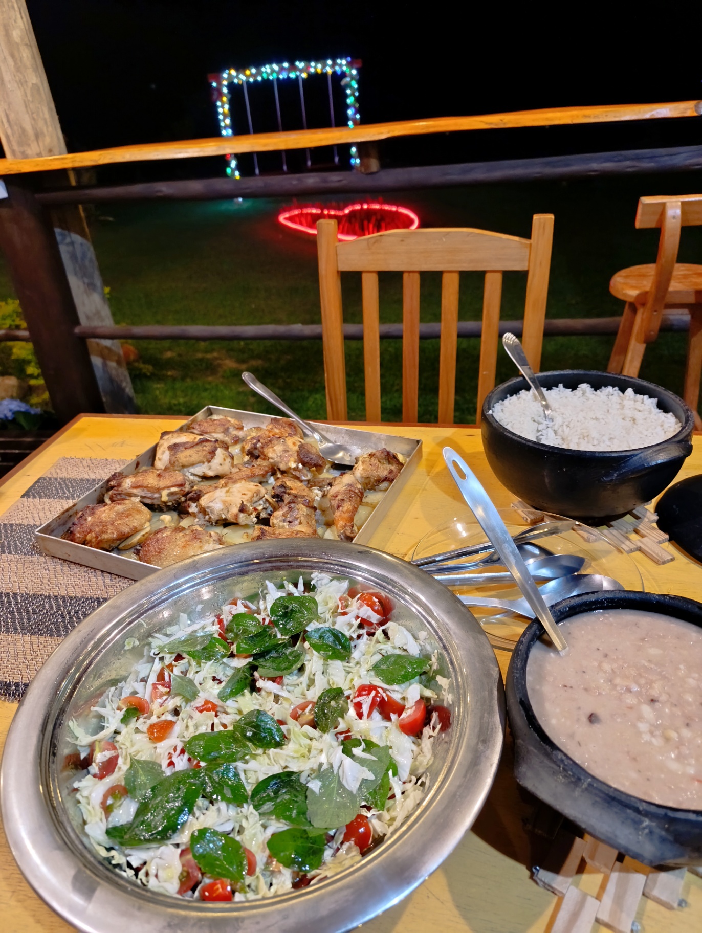 Frango assado, arroz, salada e feijão na varanda à noite
